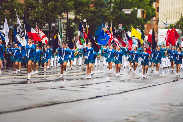 a group of people walking down a street holding flags, a tilt shift photo, by Nicolette Macnamara, pexels contest winner, process art, teal uniform, sport, toronto, panoramic view of girl