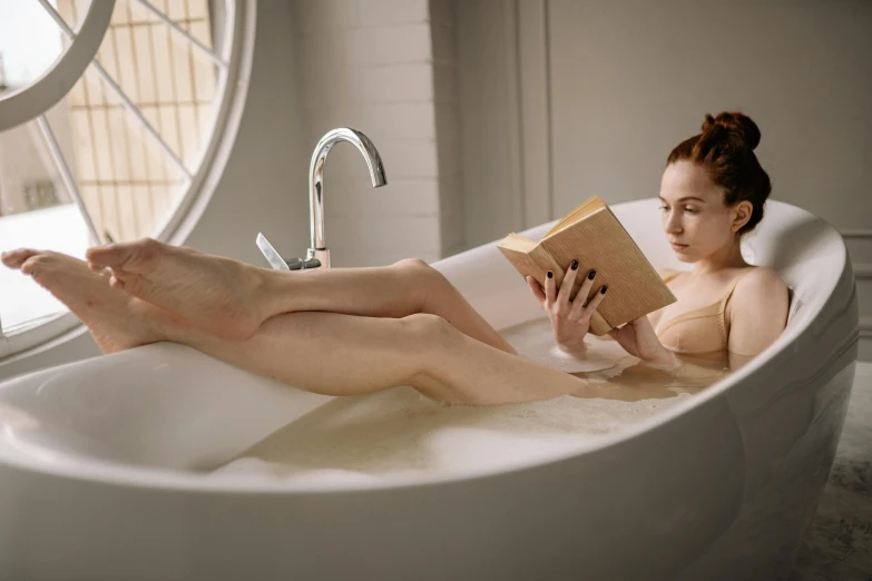 a woman sitting in a bathtub reading a book, inspired by William Stott, trending on pexels, round thighs, with pale skin, gif, high quality upload