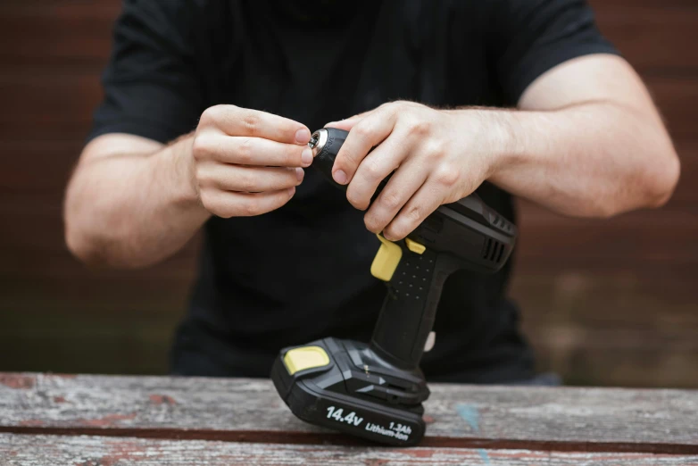 a man using a cordless drill to fix a piece of wood, by Matthias Stom, unsplash, photorealism, holding a battery, vandalism, high resolution product photo, shot on sony a 7