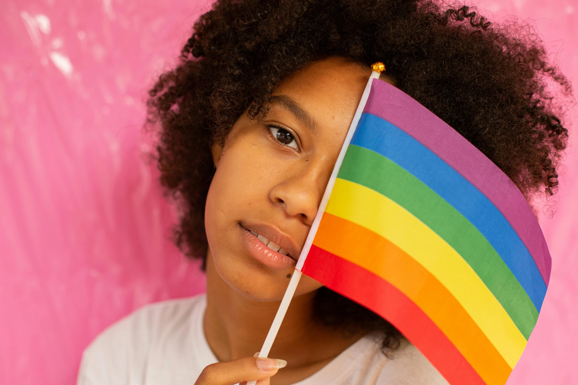 a young girl holding a rainbow flag against a pink background, trending on pexels, light-brown skin, teenage boy, thumbnail, with a white background