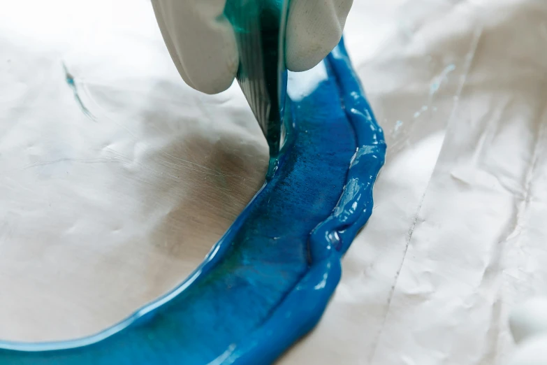 a close up of a person using a pair of scissors, inspired by Lynda Benglis, blue liquid and snow, piping, baking artwork, white and teal metallic accents