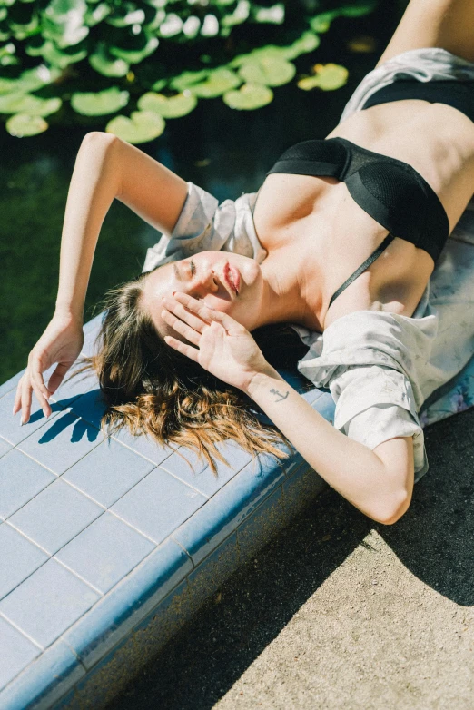 a woman in a bikini laying on top of a pool, inspired by Elsa Bleda, unsplash, renaissance, woman very tired, in the sun, low cut top, black bikini