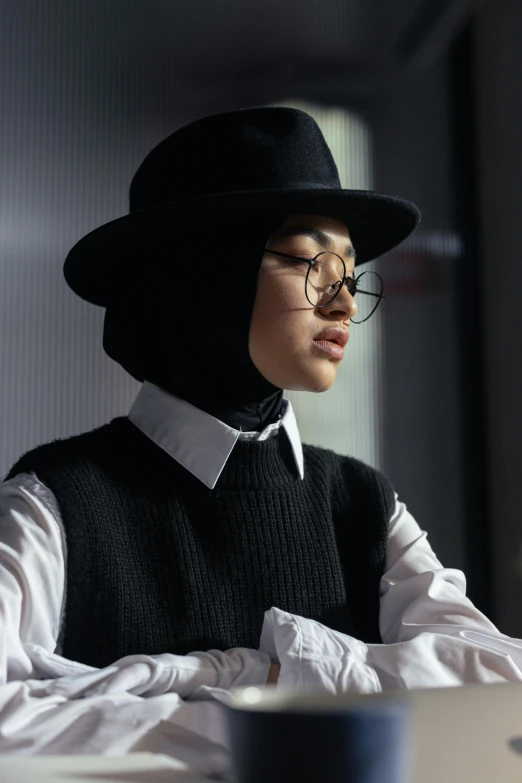 a woman sitting in front of a laptop computer, a character portrait, inspired by Bernardino Mei, trending on pexels, hurufiyya, black hat, in white turtleneck shirt, academic clothing, bella poarch