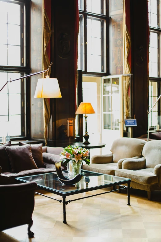 a living room filled with furniture and lots of windows, inspired by Ramon Pichot, unsplash, art nouveau, gentleman's club lounge, castle great hall, nate berkus, cozy arm chairs