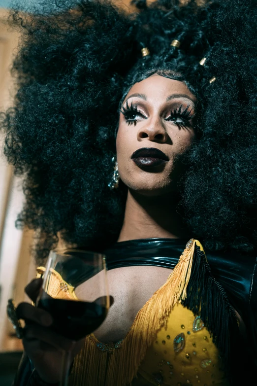 a woman in a yellow dress holding a glass of wine, an album cover, trending on pexels, renaissance, ru paul\'s drag race, black velvet, headshot, 3 5 mm photo