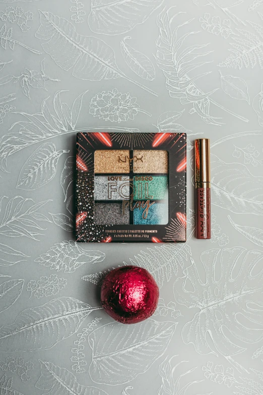 a christmas ornament with a red ornament next to it, inspired by Eden Box, pop art, smokey eye, gold and teal color scheme, full product shot, light holographic tones