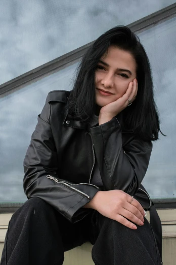 a woman sitting on a ledge in front of a window, an album cover, inspired by Marina Abramović, pexels contest winner, dressed in leather jacket, photo of sheryl sandberg, olga buzova, profile image