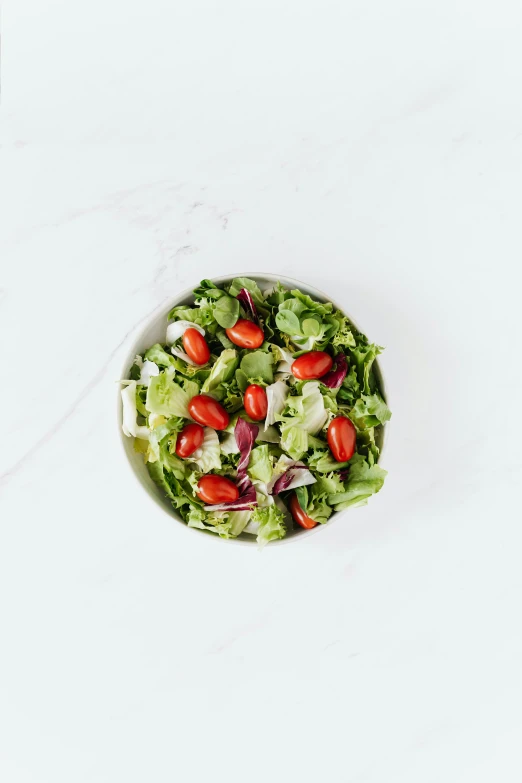 a bowl of salad sitting on top of a white table, detailed product image, front facing, organic color, lightly dressed