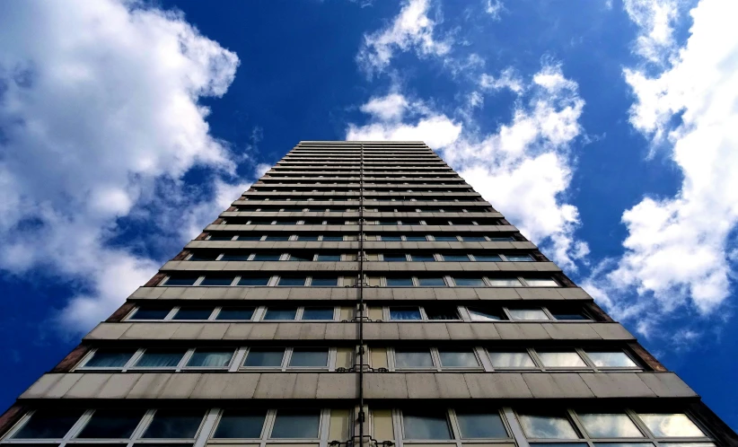 a tall building with lots of windows and a sky background, inspired by Richard Wilson, unsplash, brutalism, ten flats, slide show, bright blue sky, towering high up over your view