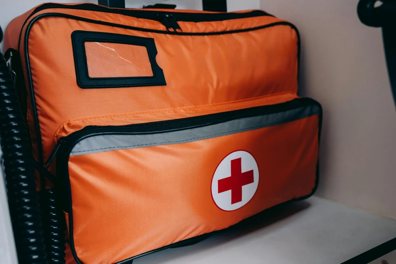 an orange bag with a red cross on it, a photo, pexels, hurufiyya, medical equipment, profile image, view from side, front closeup