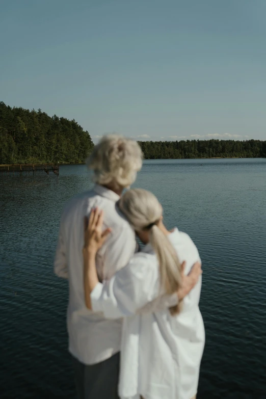 a couple of people standing next to each other near a body of water, by Jaakko Mattila, silver haired, cinematic footage, celebration, ignant