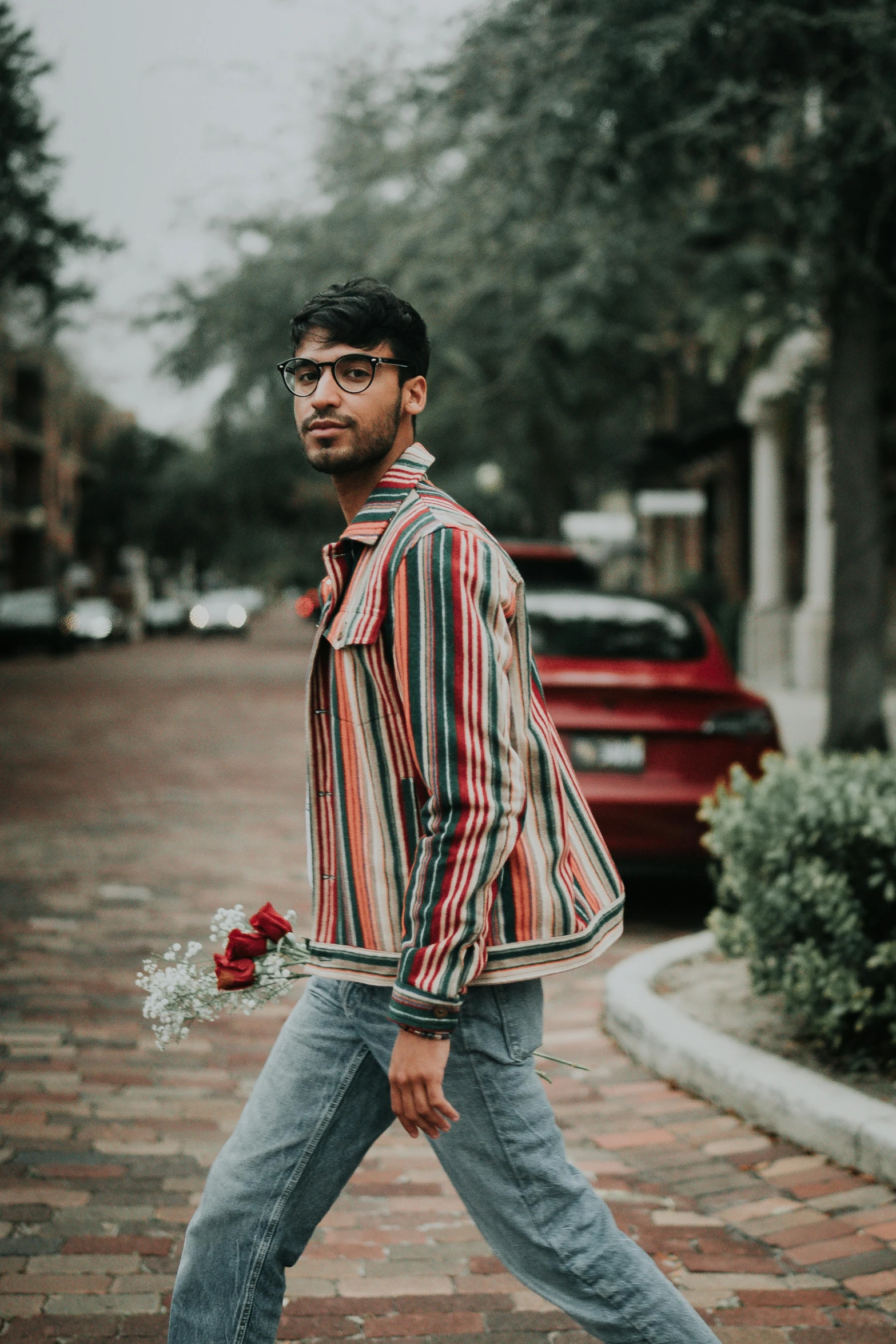 a man walking down the street with a bouquet of flowers, an album cover, pexels contest winner, wearing stripe shirt, provocative indian, man with glasses, confident pose