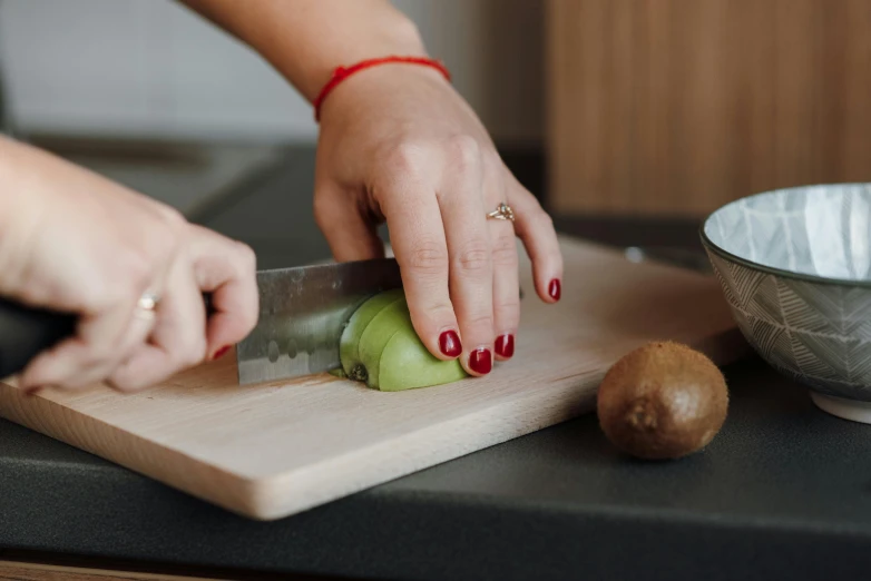 a woman is cutting an avocado on a cutting board, by Julia Pishtar, pexels contest winner, back of hand on the table, kiwi, matte finish, enamel