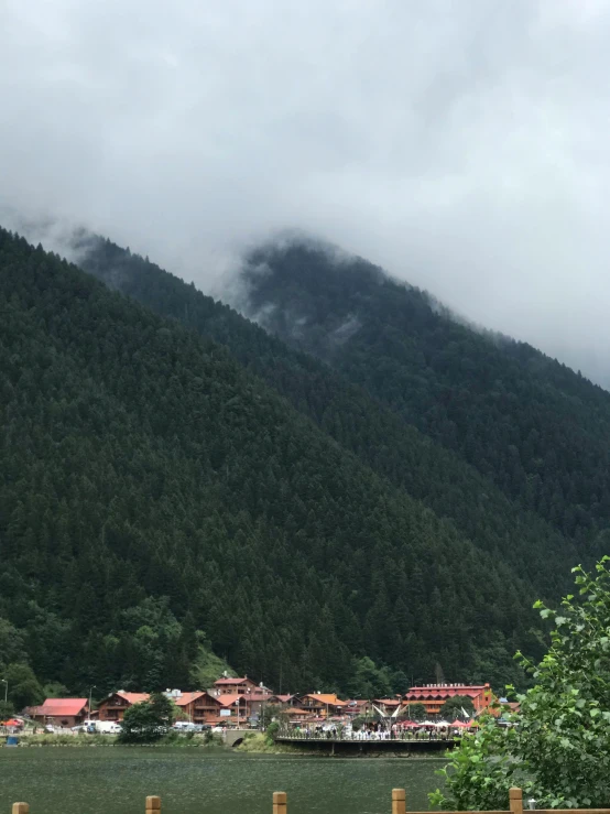 a bench sitting on the side of a road next to a body of water, by Muggur, hurufiyya, mist below buildings, fir forest, profile image, looking down at the valley