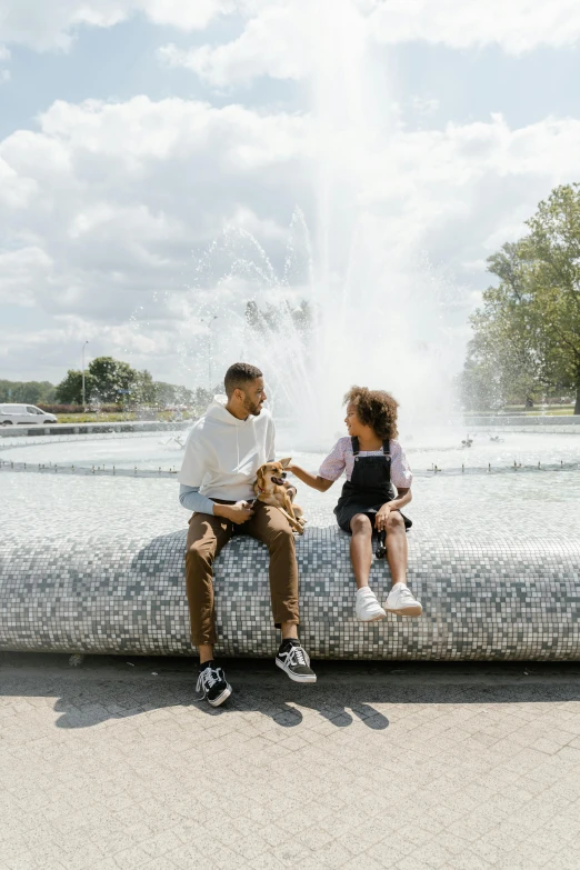 a man and a woman sitting on a stone bench in front of a fountain, by Washington Allston, pexels contest winner, with a kid, paris, teddy fresh, daughter