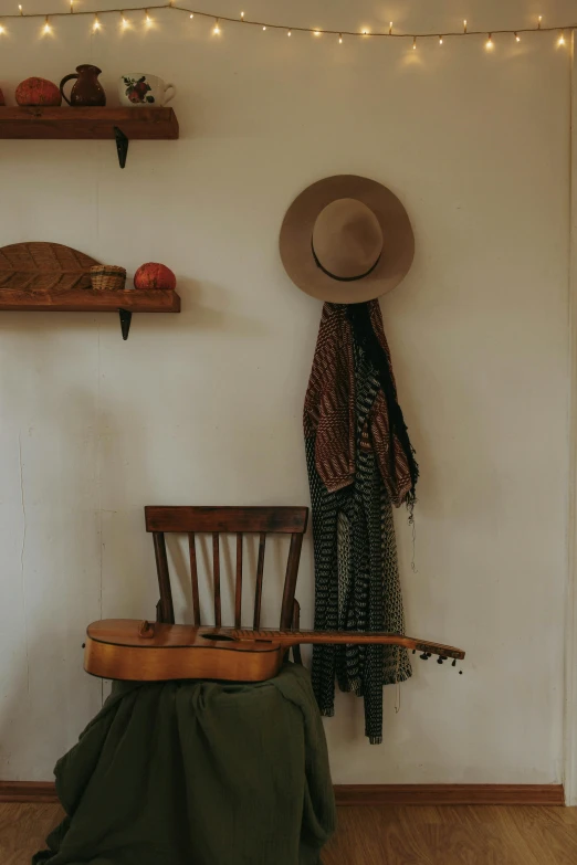 a wooden chair sitting in a living room under a string of lights, by Jessie Algie, unsplash, conceptual art, straw hat and overcoat, real guitars hanging on the wall, cloth accessories, traveling clothes