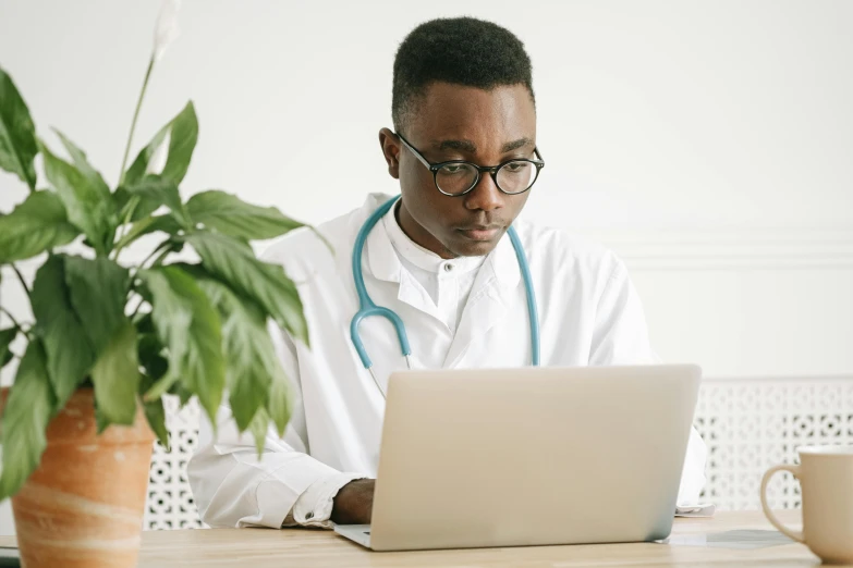 a man with a stethoscope sitting in front of a laptop, by Carey Morris, pexels, renaissance, wearing lab coat and glasses, avatar image, afro tech, a wooden