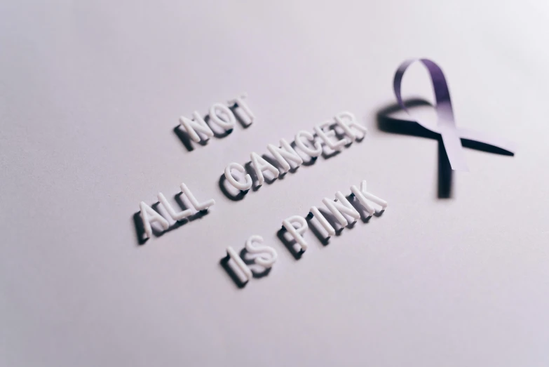 a purple ribbon with the words not all cancer is fatal, a photo, pexels contest winner, antipodeans, paper cutout, monochromatic photo, alexis franklin, mind