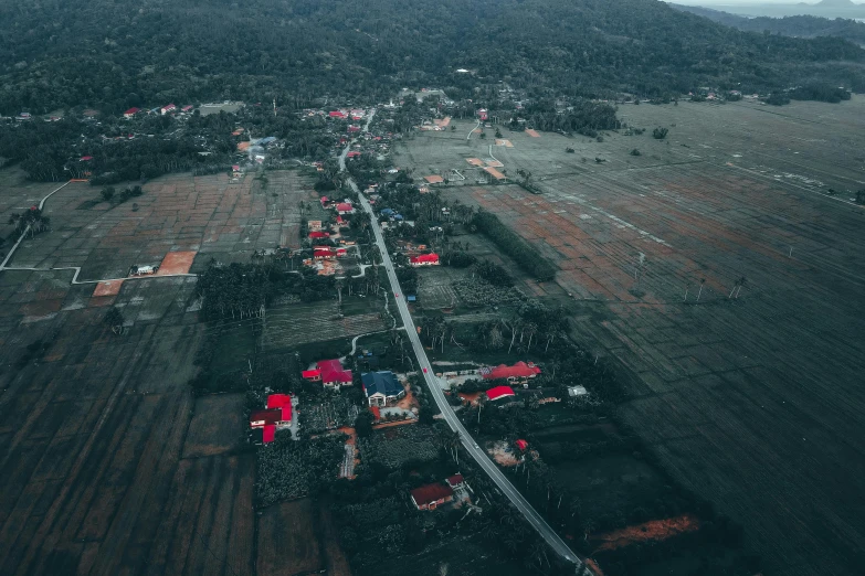 an aerial view of a village with mountains in the background, pexels contest winner, hurufiyya, dark gloomy, south jakarta, slightly red, devastation