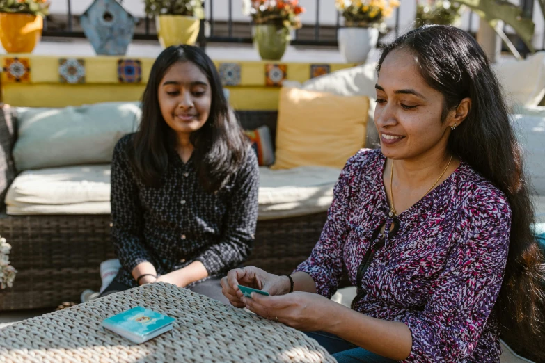 two women sitting at a table with a cell phone, pexels contest winner, hurufiyya, cardistry, at the terrace, avatar image, family friendly