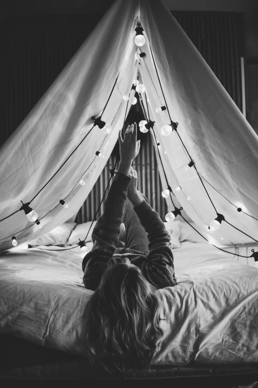 a woman laying on top of a bed under a canopy, tumblr, string lights, black and white image, instagram picture, black & white photo