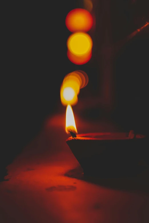 a lit candle sitting on top of a table, by Max Dauthendey, pexels, light and space, red and yellow light, instagram picture, buddhist, festivals