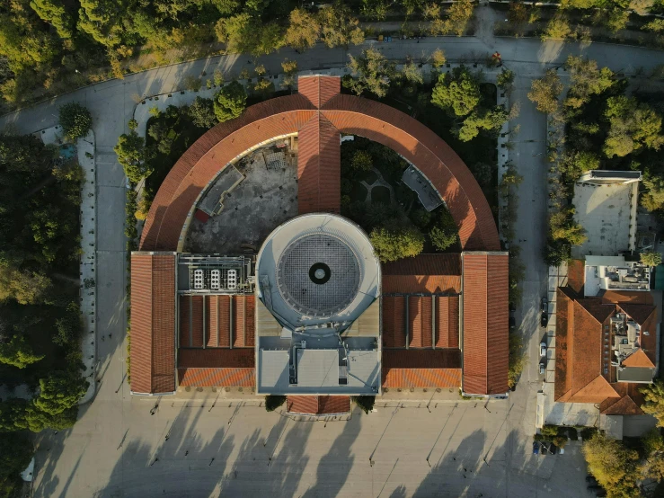 an aerial view of a building surrounded by trees, pexels contest winner, photorealism, curving geometric arches, helipad, turkey, circular face