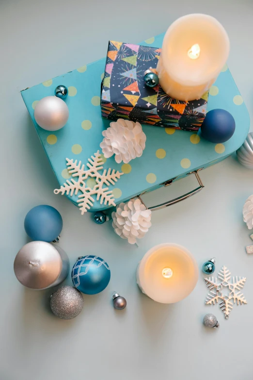 a blue present sitting on top of a table next to a lit candle, ornaments, knolling, thumbnail, various items