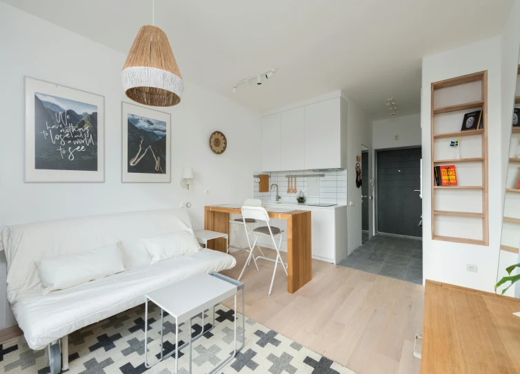 a white couch sitting in a living room next to a kitchen, by Adam Marczyński, unsplash, small and cosy student bedroom, studio photo, seaview, listing image