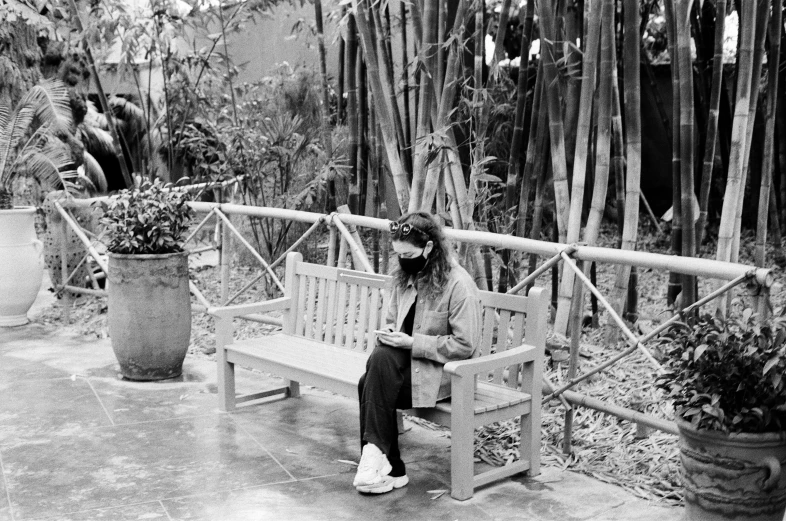 a black and white photo of a woman sitting on a bench, visual art, in the zoo exhibit, hozier, musician, of bamboo