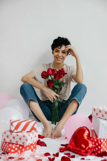 a woman sitting on a bed holding a bouquet of roses, a cartoon, pexels contest winner, curly pixie cut hair, party balloons, jeans and t shirt, red hearts