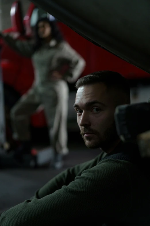 a man sitting in the driver's seat of a car, a portrait, by David Begbie, hurufiyya, wearing human air force jumpsuit, **cinematic, multicam (camo), rhys lee