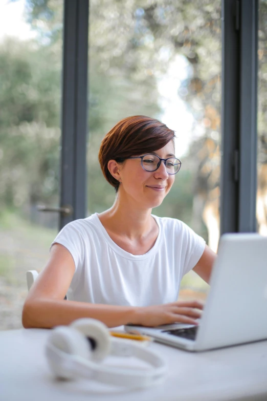 a woman sitting at a table using a laptop computer, pexels contest winner, renaissance, white reading glasses, low quality photo, delightful surroundings, full frame image