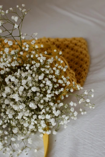 a bouquet of baby's breath sits on a bed, by artist, unsplash, knitted hat, yellow aureole, detail shot, honeycomb