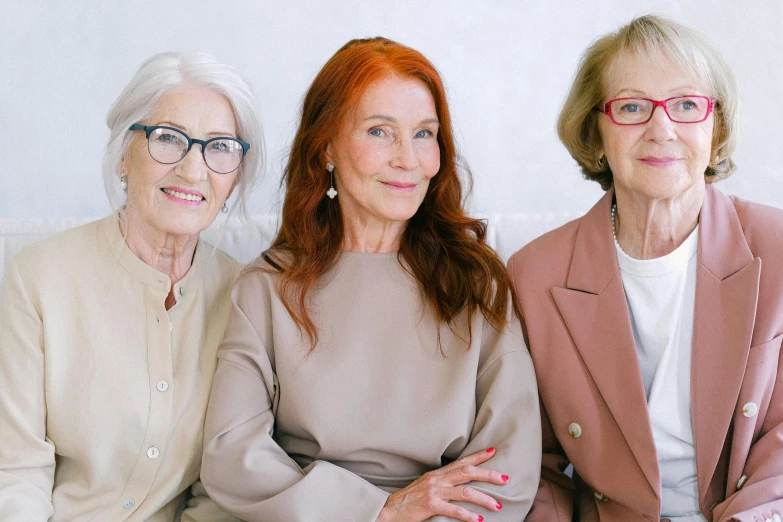 three women sitting next to each other on a couch, trending on pexels, photorealism, an old lady with red skin, photoshoot for skincare brand, woman with red hair, the look of an elderly person