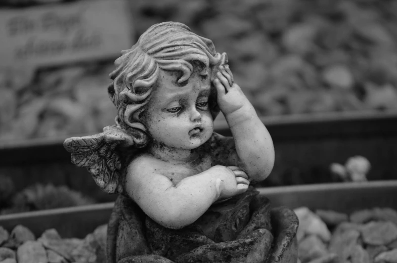 a black and white photo of a little angel, a statue, by Joze Ciuha, pixabay contest winner, realism, he has a devastated expression, selective color effect, ornately detailed, beautiful cute