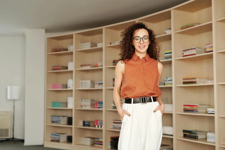 a woman standing in front of a bookshelf, eliran kantor, with hands in pockets, portrait image, architect