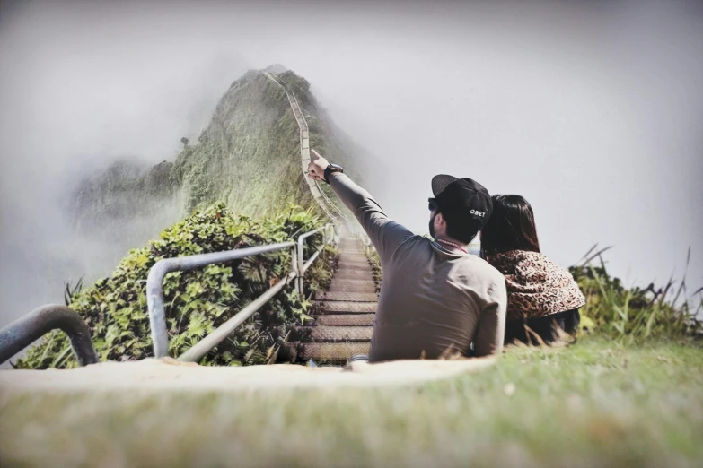 a man and a woman taking a picture of a mountain, a picture, by Lucia Peka, pexels contest winner, romanticism, stairway to heaven, ( ( ( ( kauai ) ) ) ), low angle mist, sitting on man's fingertip