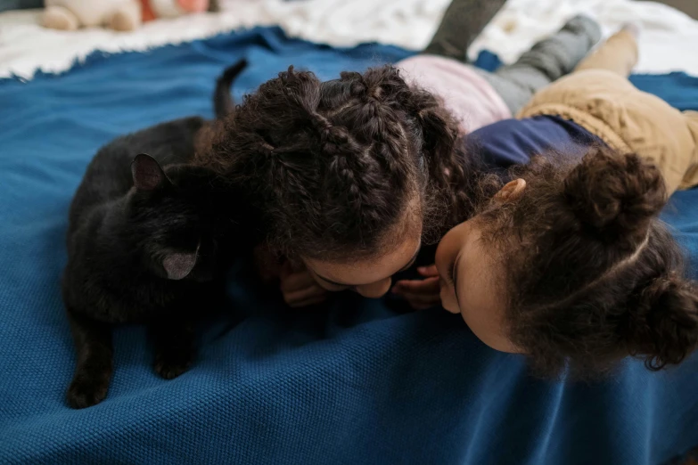 a couple of kids laying on top of a bed with a cat, by Julia Pishtar, pexels contest winner, blue and black scheme, portrait of two girls kissing, ebony, close up angle