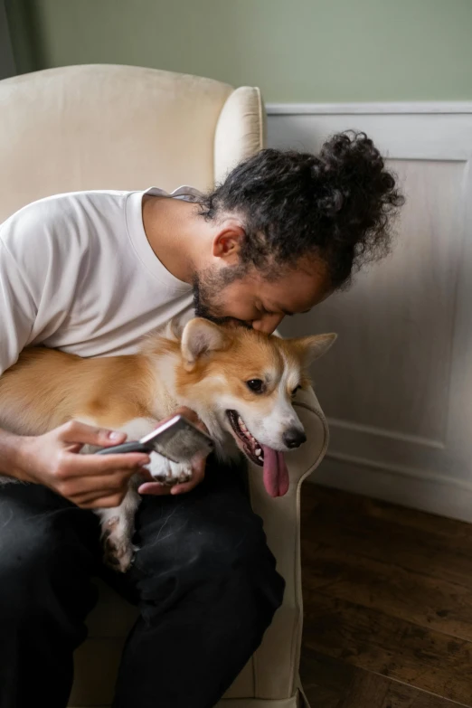 a man sitting in a chair holding a dog, trending on pexels, renaissance, chewing on a graphic card, dry brushing, kissing each other, corgi