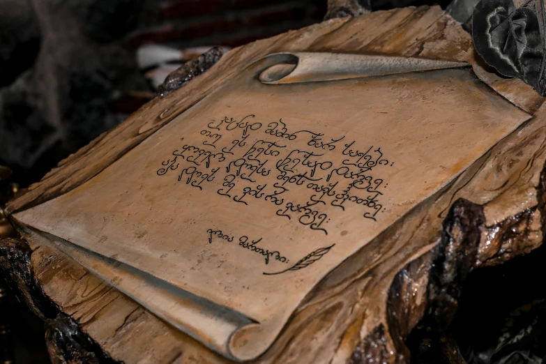 a piece of paper sitting on top of a piece of wood, elvish, caligraphy, detailed clay model, background image