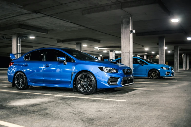 two blue cars parked in a parking lot, inspired by An Gyeon, pexels contest winner, wrx golf, in an underground parking garage, avatar image, samurai vinyl wrap