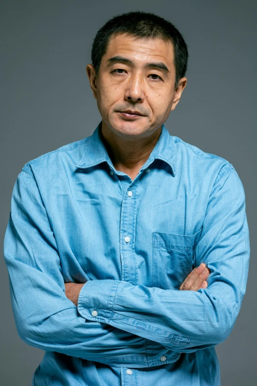 a man in a blue shirt standing with his arms crossed, inspired by Yasushi Sugiyama, promotional image, headshot photograph, murata, shotaro ishinomori