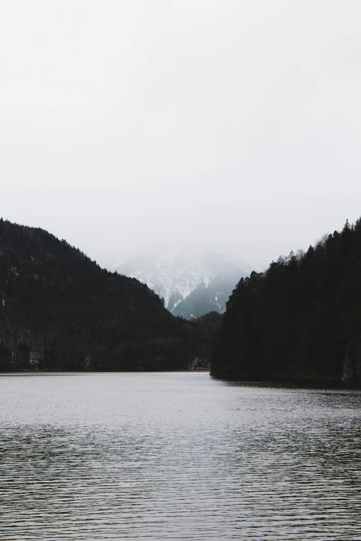 a body of water with mountains in the background, a picture, by Sebastian Spreng, trending on unsplash, romanticism, gloomy forest, low quality photo, grey, multiple stories