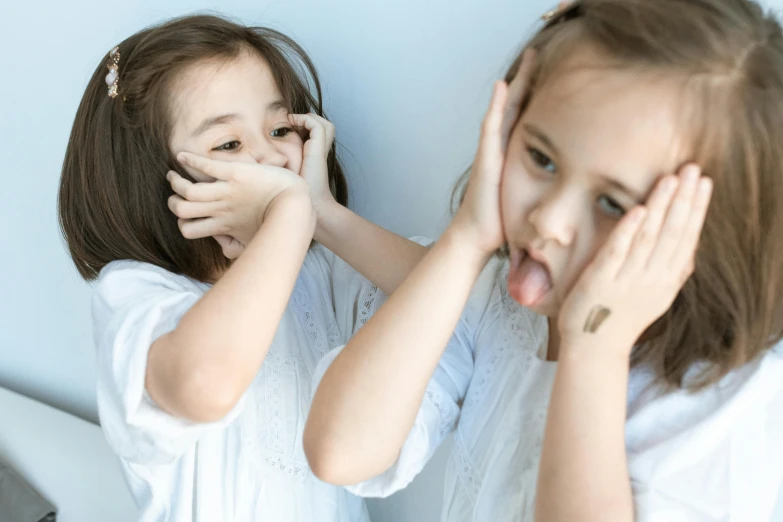 a couple of little girls standing next to each other, trending on pexels, fleshy creature above her mouth, hands shielding face, two models in the frame, thumbnail