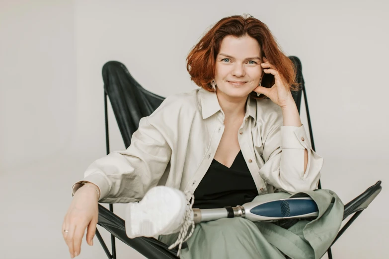 a woman sitting in a chair talking on a cell phone, an album cover, by Emma Andijewska, pexels contest winner, renaissance, prosthetic limbs, relaxing and smiling at camera, anastasia ovchinnikova, with electric arc device