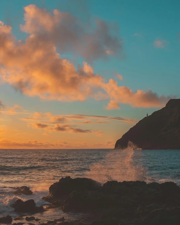 a man standing on top of a rock next to the ocean, pexels contest winner, romanticism, orange / pink sky, azores, fading rainbow light, today\'s featured photograph 4k