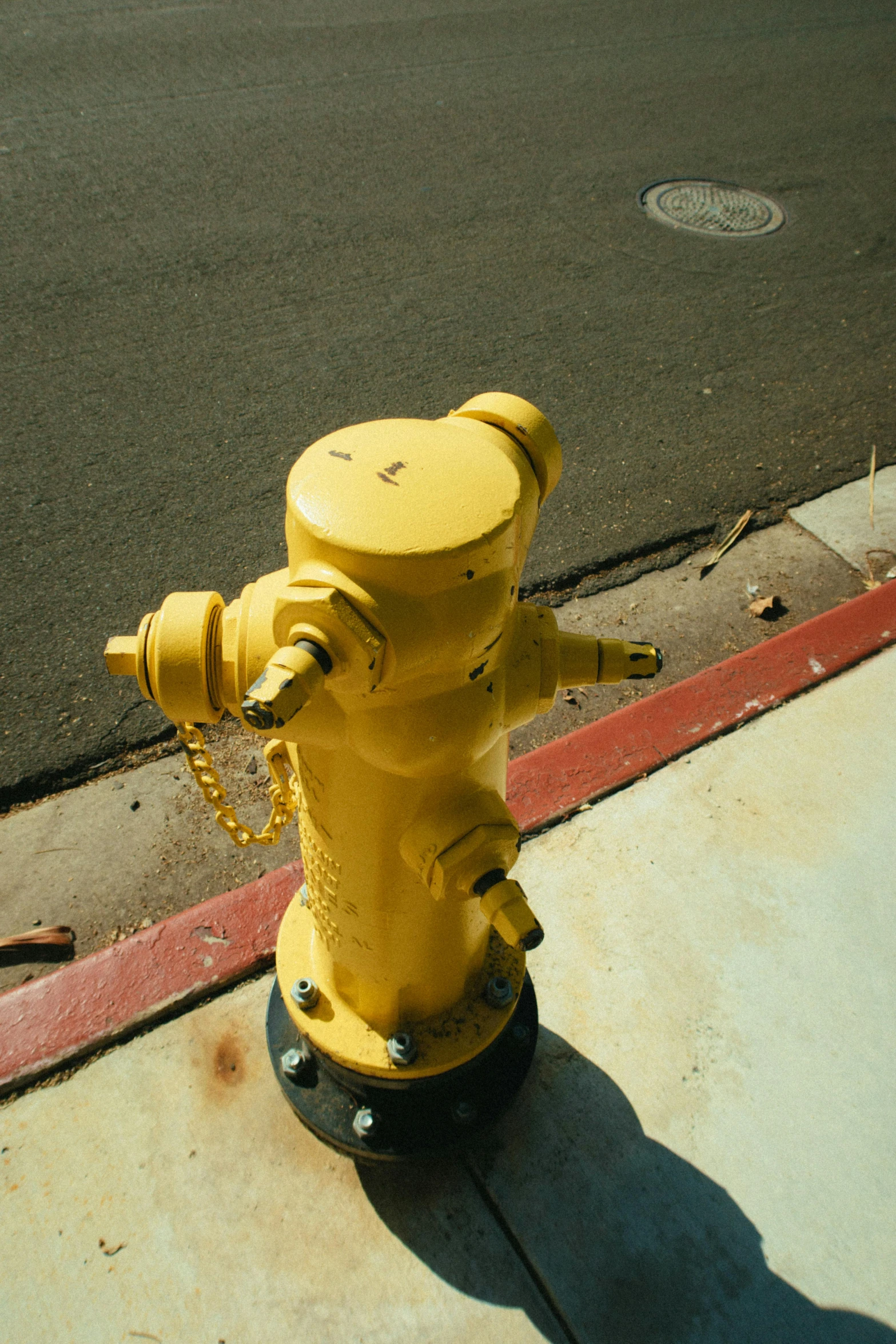 a yellow fire hydrant sitting on the side of a road, taken in the mid 2000s, photograph from above, square, four legged