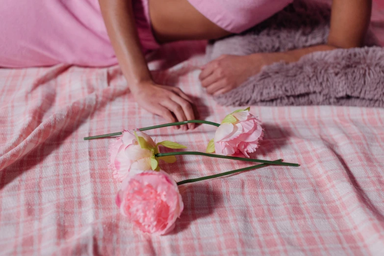 a woman laying on top of a bed next to flowers, inspired by Peter Alexander Hay, trending on pexels, pink pastel, flannel, holding magic flowers, on a velvet tablecloth