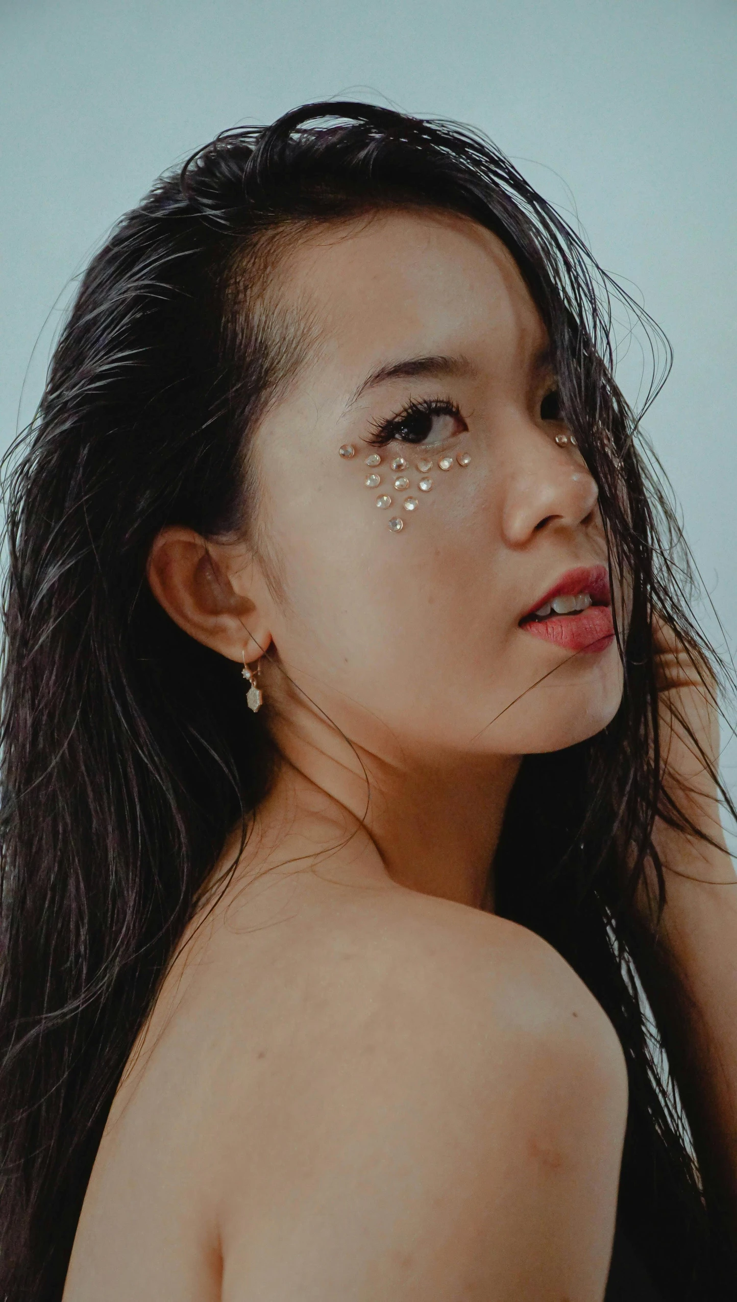 a woman standing on top of a beach next to the ocean, an album cover, inspired by Natasha Tan, trending on pexels, hyperrealism, glitter makeup, young cute wan asian face, earring, golden inlays